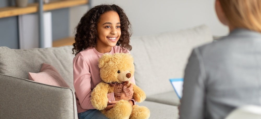 Girl holding teddy bear in child therapy session