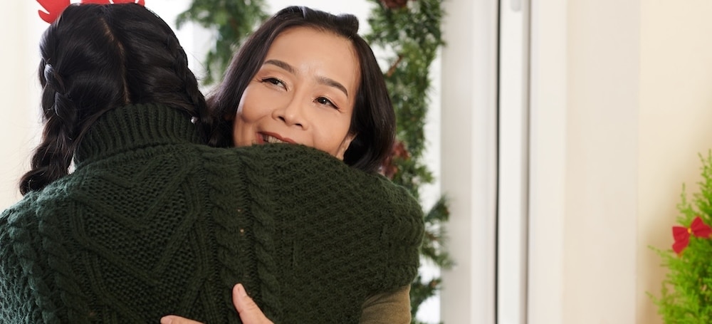 Smiling woman hugging adult daughter at holiday party