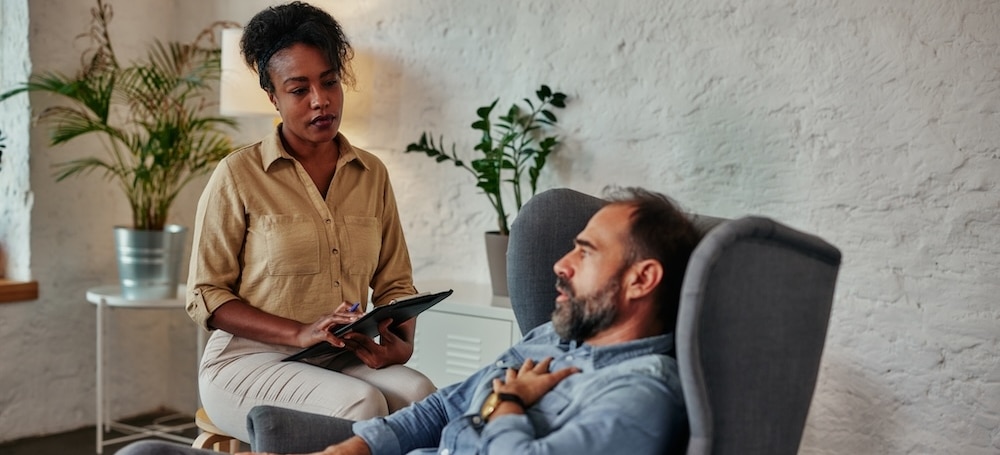 Upset man having therapy session with female psychiatrist